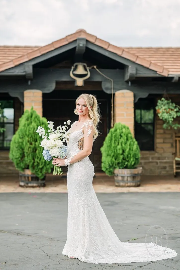 Bride holding her bouquet in front of the villa and its bell