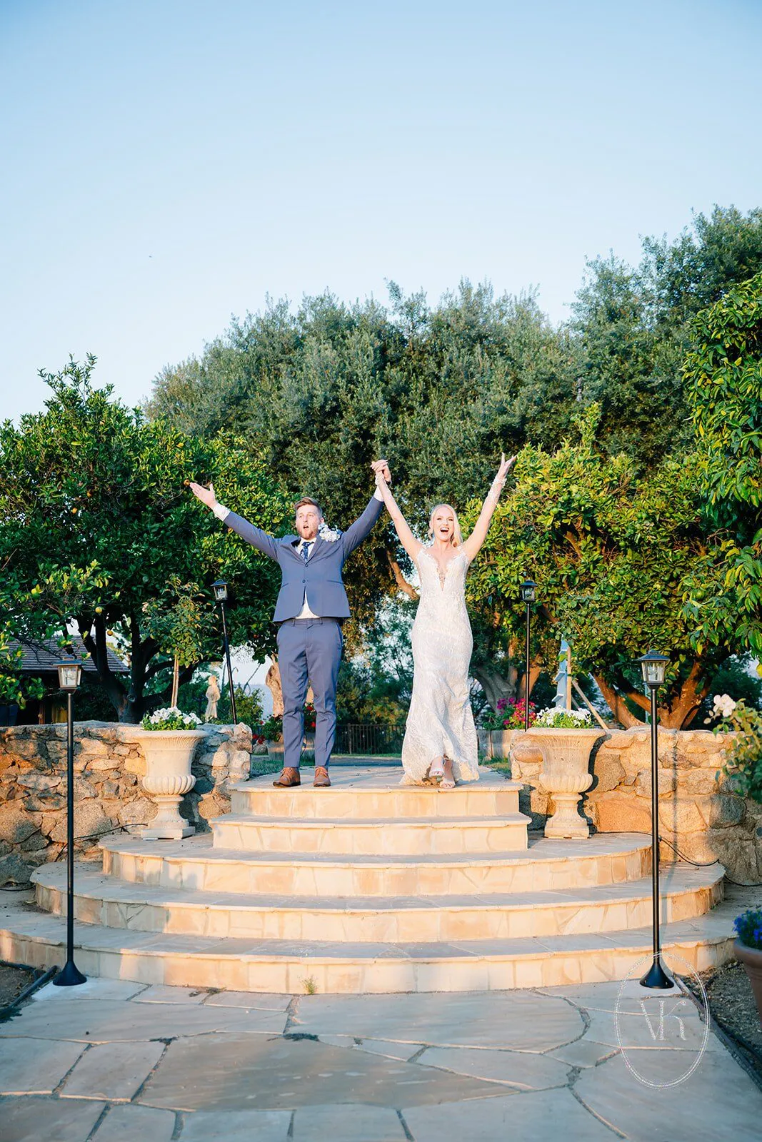 Newly married couple celebrating with raised arms on the stone steps of the altar at Villa San Giovese
