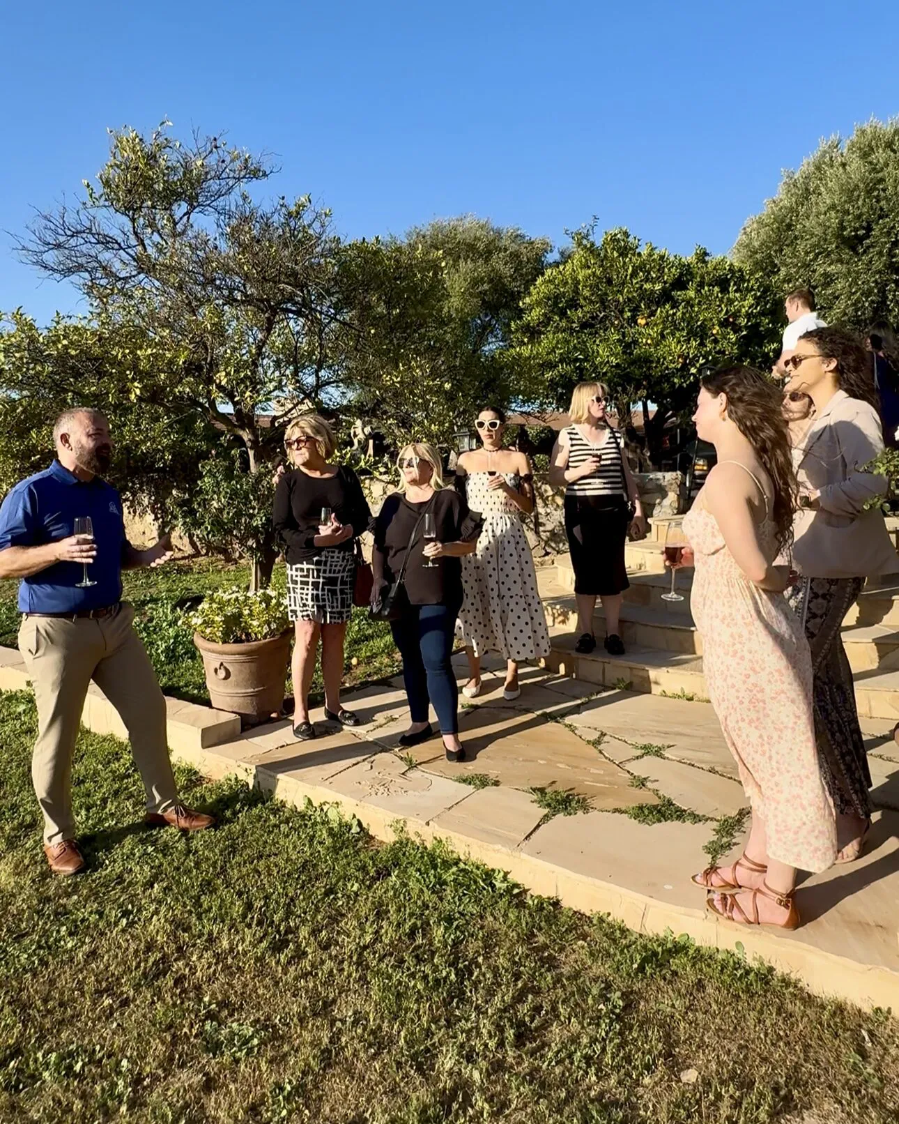 Wedding guests with glasses of wine gathered on the garden steps at Villa San Giovese