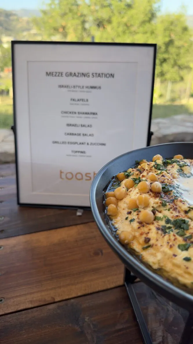 Mezze grazing station with hummus and a printed menu against the valley view