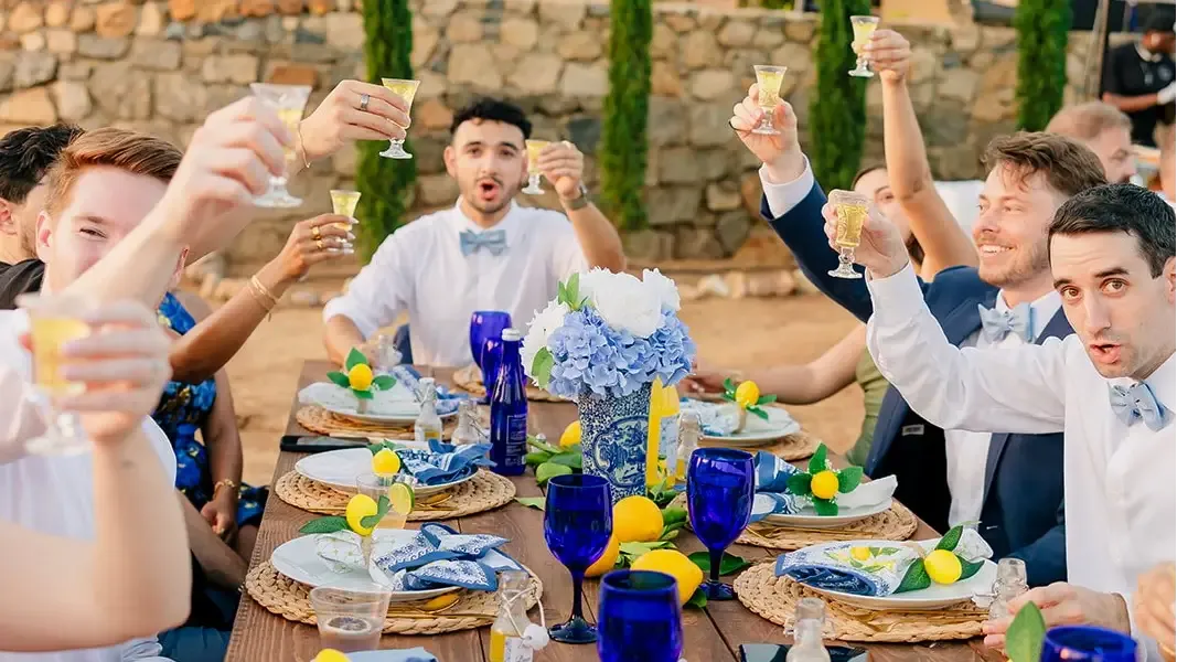 Guests raising glasses at a long table in front of the stone wall